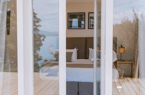 A bedroom with a bed, a nightstand, and a lamp. There are framed pictures on the wall.