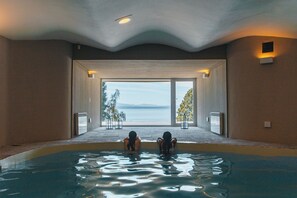 Ein Hallenbad mit zwei Personen, großen Fenstern und Blick ins Freie.