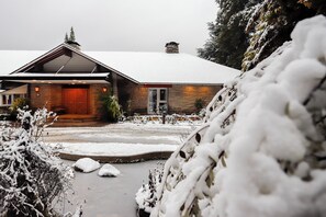 Uma casa de pedra com telhado coberto de neve e porta de madeira.
