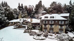 A multi-story hotel with a snow-covered landscape, surrounded by trees. - La Cascada Casa Patagónica by DON (San Carlos de Bariloche)
