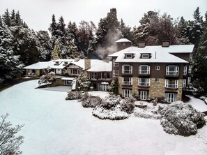 Ein mehrstöckiges Hotel inmitten einer verschneiten Landschaft, umgeben von Bäumen.