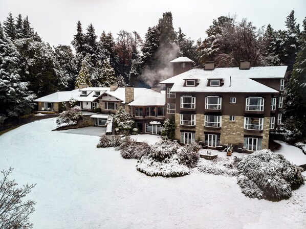 Um hotel com vários andares em meio a uma paisagem coberta de neve, rodeado por árvores.