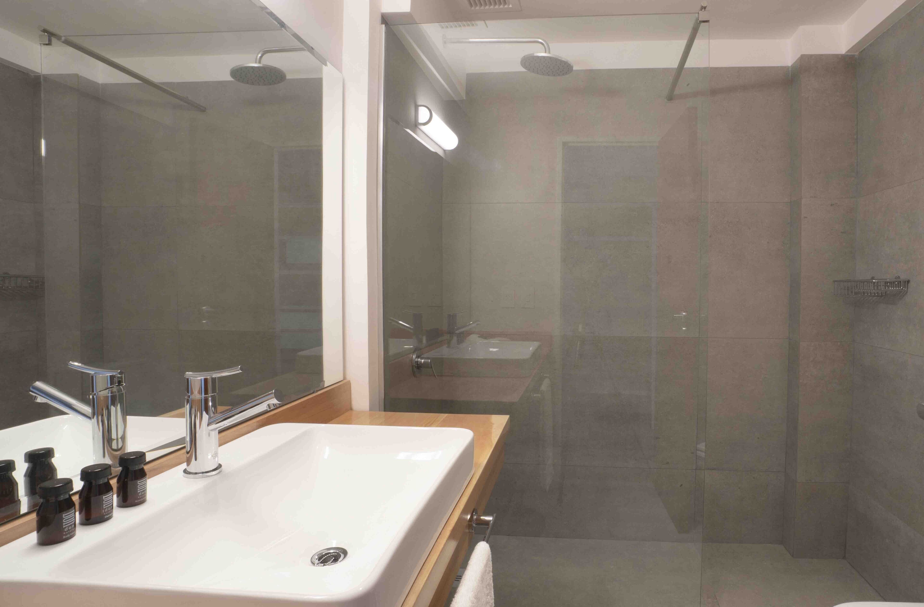A modern bathroom with a large mirror, a white sink, and a glass-enclosed shower area.