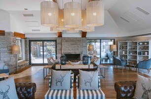 Un salón amplio con chimenea de piedra, sofás a rayas y una mesa de centro de madera.