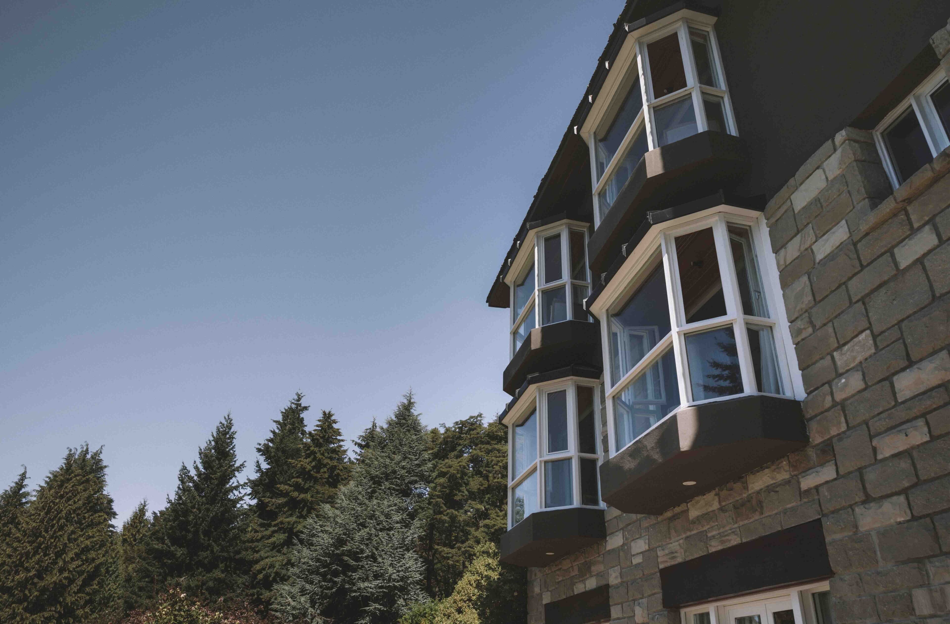 A multi-story building with stone exterior and multiple bay windows.