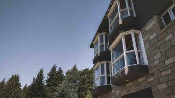A multi-story building with stone exterior and multiple bay windows.