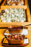 Uma tigela com mistura de frutos secos e frutas cristalizadas sobre um prato, com uma colher.
