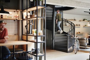 Um interior moderno com uma escada em espiral, prateleiras de madeira e uma área de jantar.