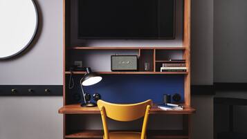 A workspace with a desk, chair, lamp, and a flat-screen TV mounted on the wall.