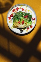 Insalata in una ciotola con verdure a foglia verde, noci e frutti di bosco su un piatto bianco.