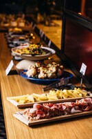 Uma mesa de buffet com diversos alimentos, incluindo queijos, carnes e saladas.