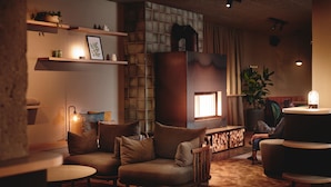Een gezellige woonkamer met een open haard, comfortabele zitplaatsen en planken met decoratieve objecten.