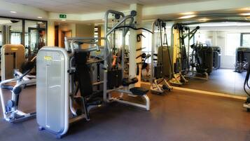 Een sportschool met diverse fitnessapparaten, spiegels en een schoon, goed verlicht interieur.