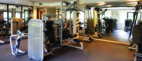 A gym with various exercise machines, mirrors, and a clean, well-lit interior.