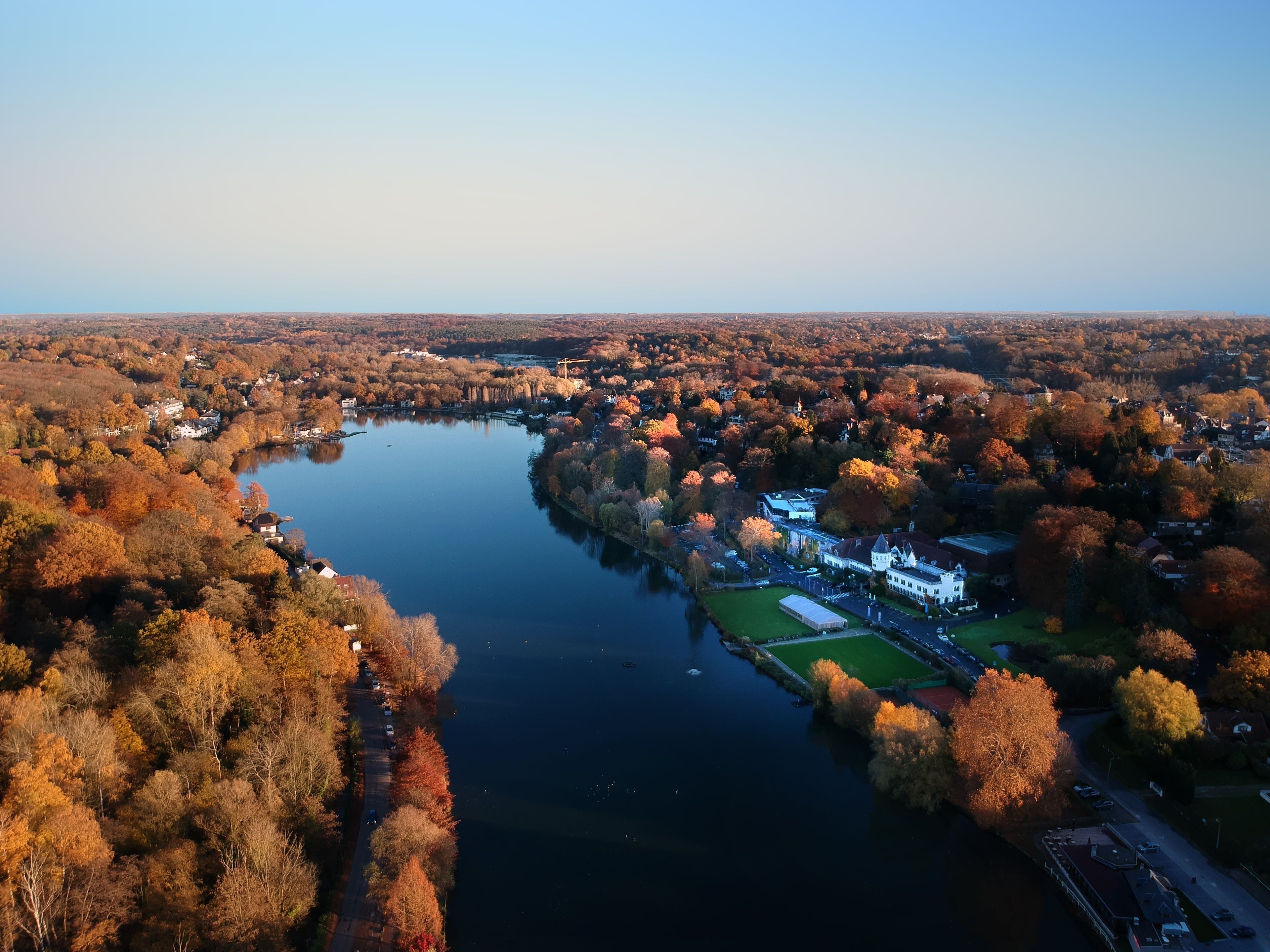 An aerial view of a lakeside town with houses, a dock, and a large building with a white facade.
