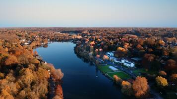 An aerial view of a lakeside town with houses, a dock, and a large building with a white facade.