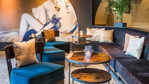 A modern lounge area with a large mural, comfortable seating, and a television screen.