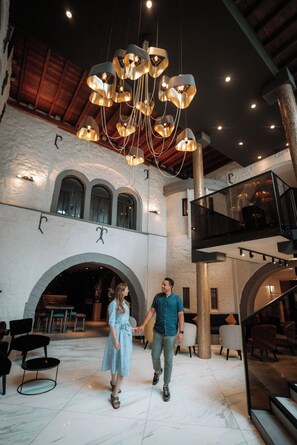 A spacious lobby with a high ceiling, modern pendant lighting, and a central arched doorway. - Martin's Château du Lac (Rixensart)