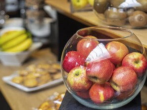 Un tazón de vidrio transparente lleno de manzanas rojas sobre una mesa de madera.