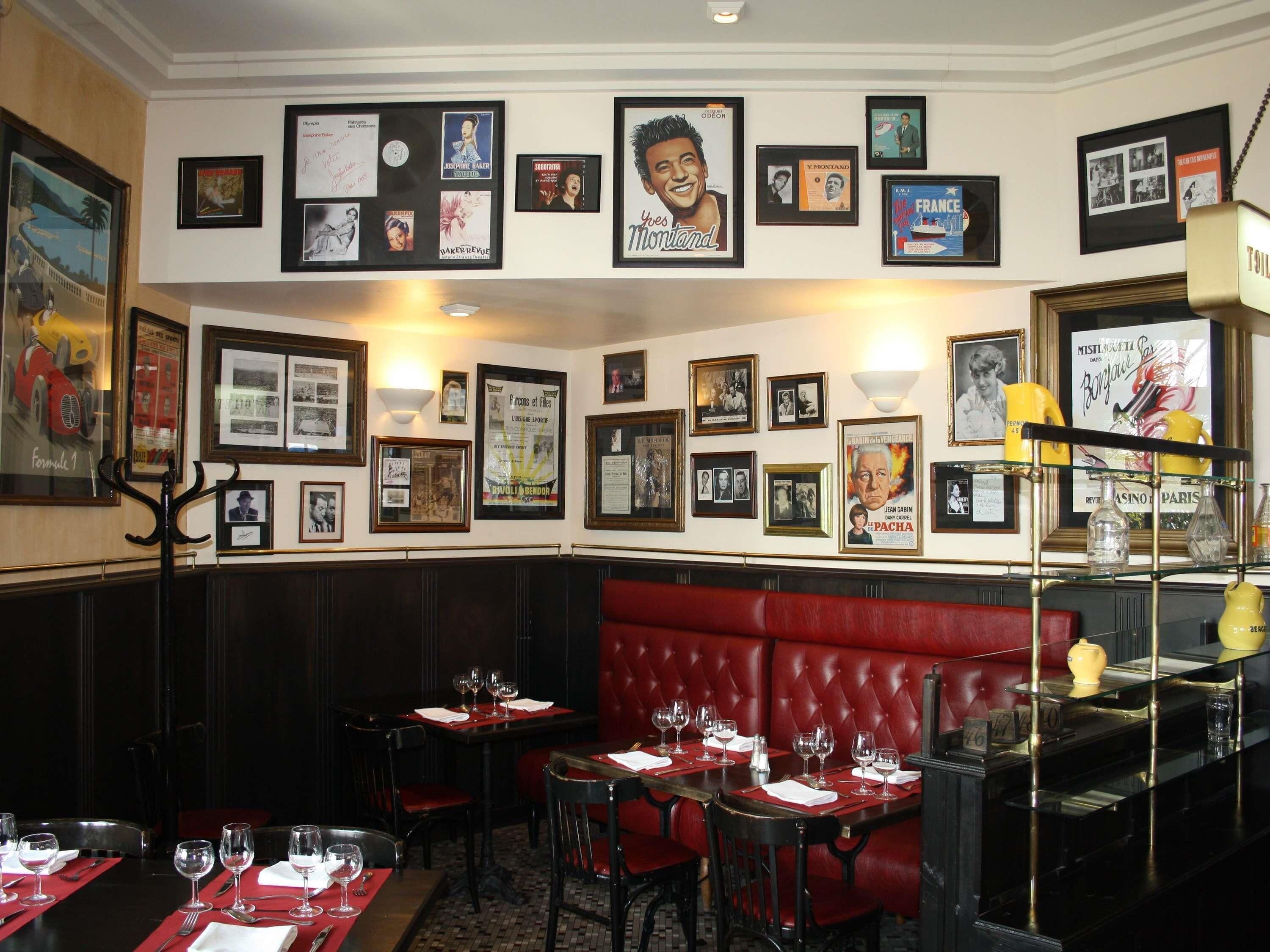 Un restaurante con asientos tipo cabina rojos, cuadros en las paredes y mesas dispuestas para comer.