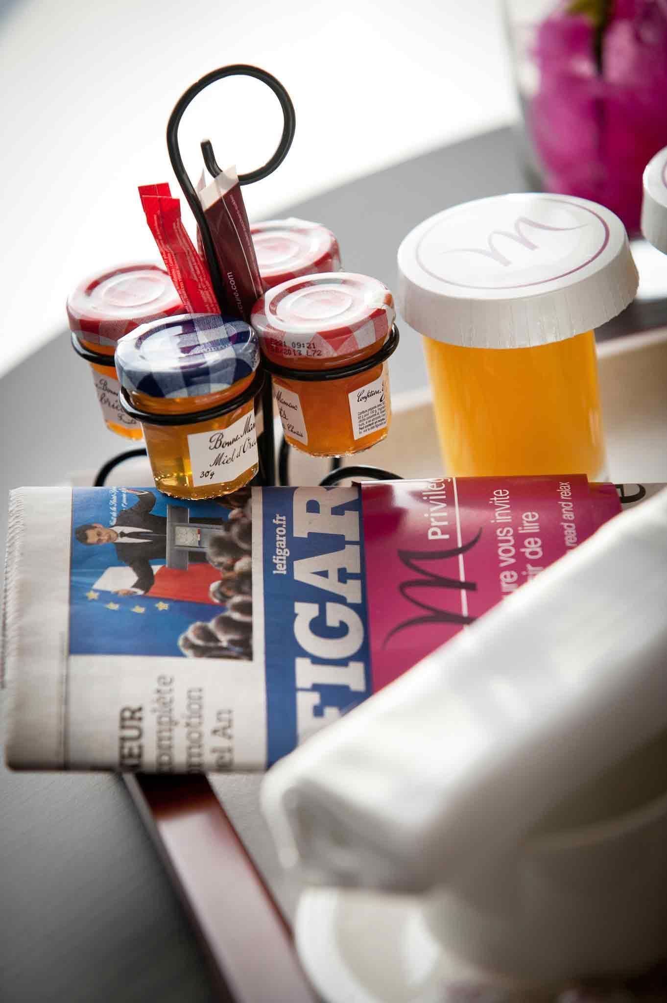 Un periódico, frascos de miel y una botella de jugo de naranja sobre una mesa.