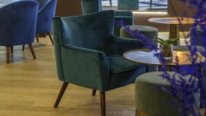 Un interior moderno con sillas color turquesa y mesas redondas, suelo de madera y vistas al exterior.