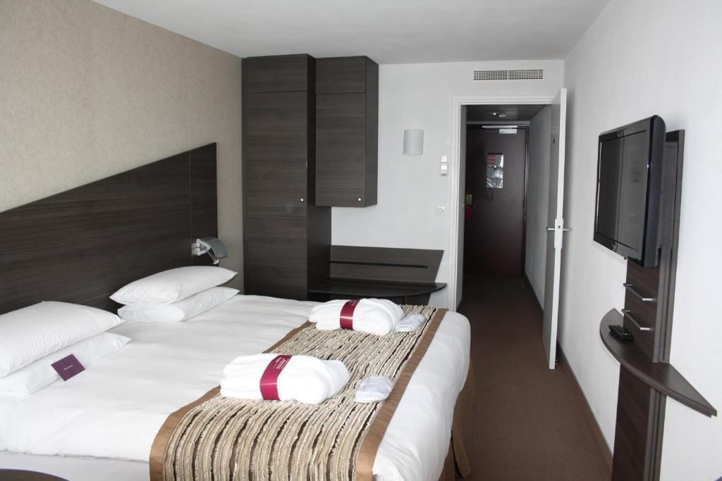 Een hotelkamer met twee bedden, een televisie, een bureau en een kledingkast.