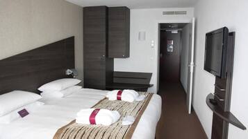 Een hotelkamer met twee bedden, een televisie, een bureau en een kledingkast.