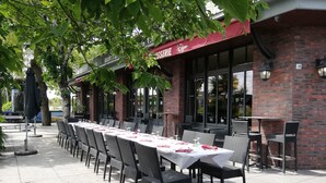 Un área de comedor al aire libre con una mesa larga preparada para varios invitados, rodeada de sillas.