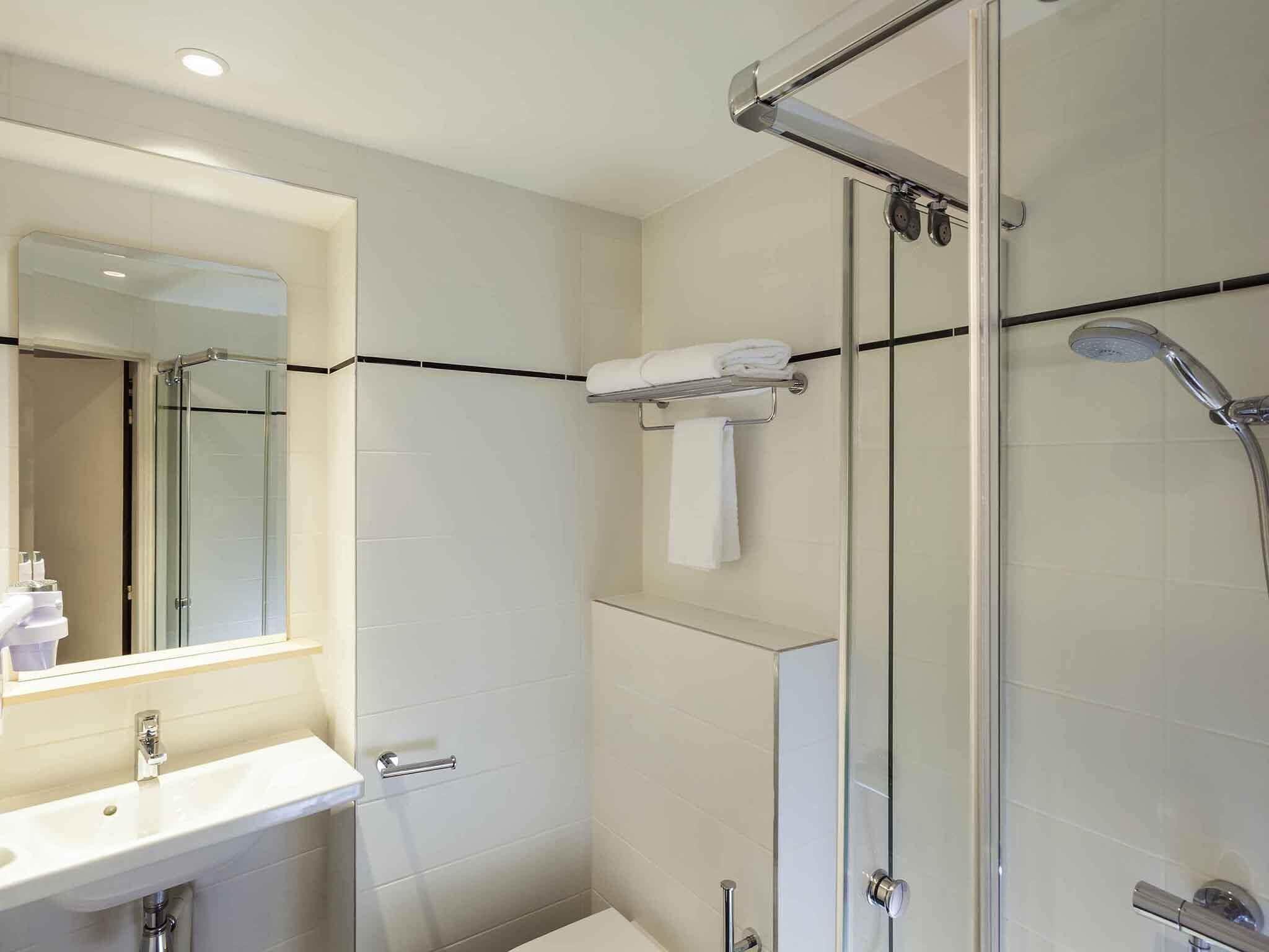 Une salle de bain moderne avec une douche à parois de verre, un lavabo avec un miroir et un porte-serviettes.
