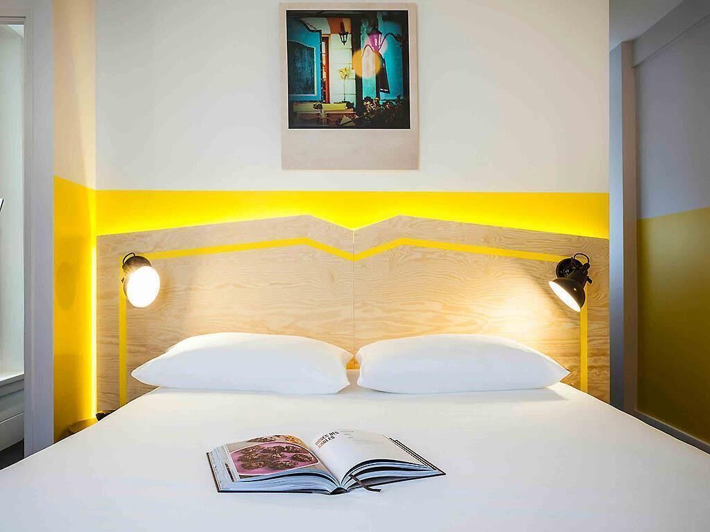 Habitació d'hotel amb un llit, dues làmpades de nit, una obra d'art penjada a la paret i una finestra.