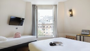 A hotel room with two beds, a TV, a laptop, and a window with a balcony view. - ibis Styles Paris Nation Porte De Montreuil (Paris)