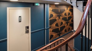 A hotel hallway with a blue wall, a patterned wall design, a door labeled '409', and a wooden staircase railing. - ibis Styles Paris Nation Porte De Montreuil (Paris)