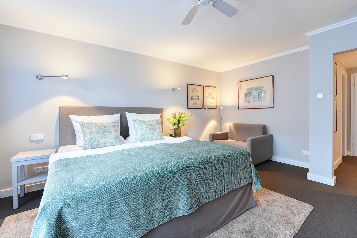 A bedroom with a bed, bedside table, nightstand, and a ceiling fan.