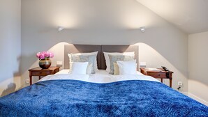 Un dormitorio con una cama, dos mesitas de noche, un florero con flores y una lámpara en el techo.