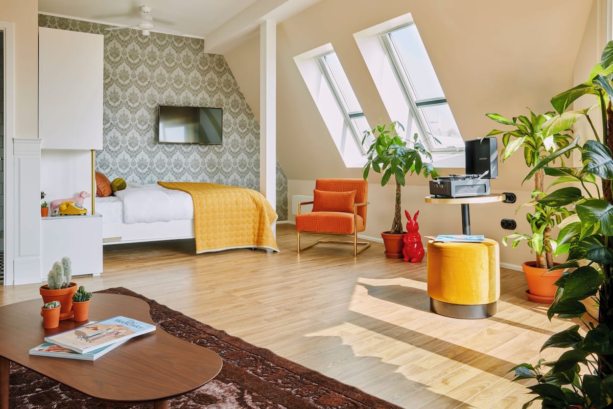 A modern bedroom with a bed, a TV, a desk, and a chair.