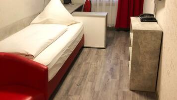 Una habitación de hotel con cama, escritorio, silla, televisor y obras de arte en las paredes.