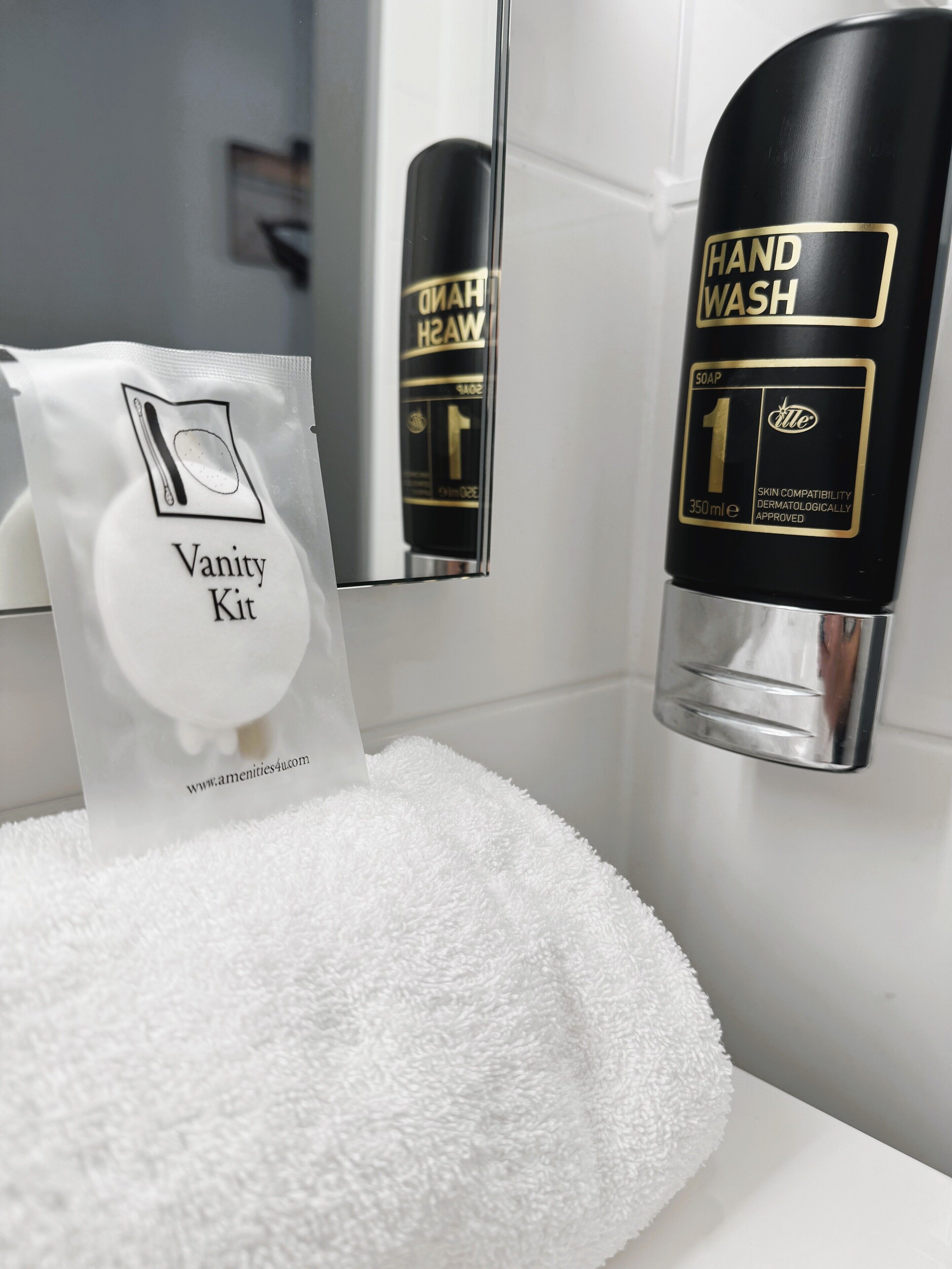 A bathroom with a hand wash station, a vanity kit, and a white towel.
