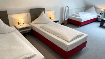 Ein Hotelzimmer mit zwei Einzelbetten, jeweils mit Nachttisch, Lampe und Wandheizung.