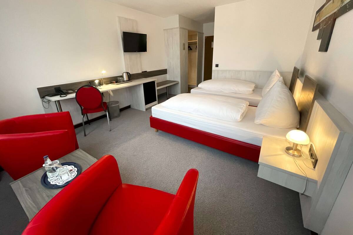 A hotel room with a bed, a desk, a chair, and a TV.
