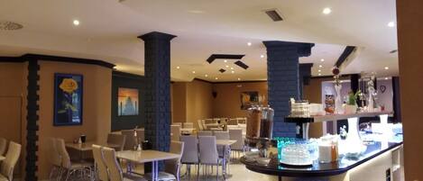 A hotel lobby with a central bar area, seating arrangements, and decorative elements.