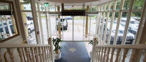 A hotel entrance with a view of the parking lot.