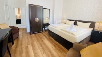 Quarto de hotel com uma cama grande, um guarda-roupa, uma escrivaninha e uma cadeira.
