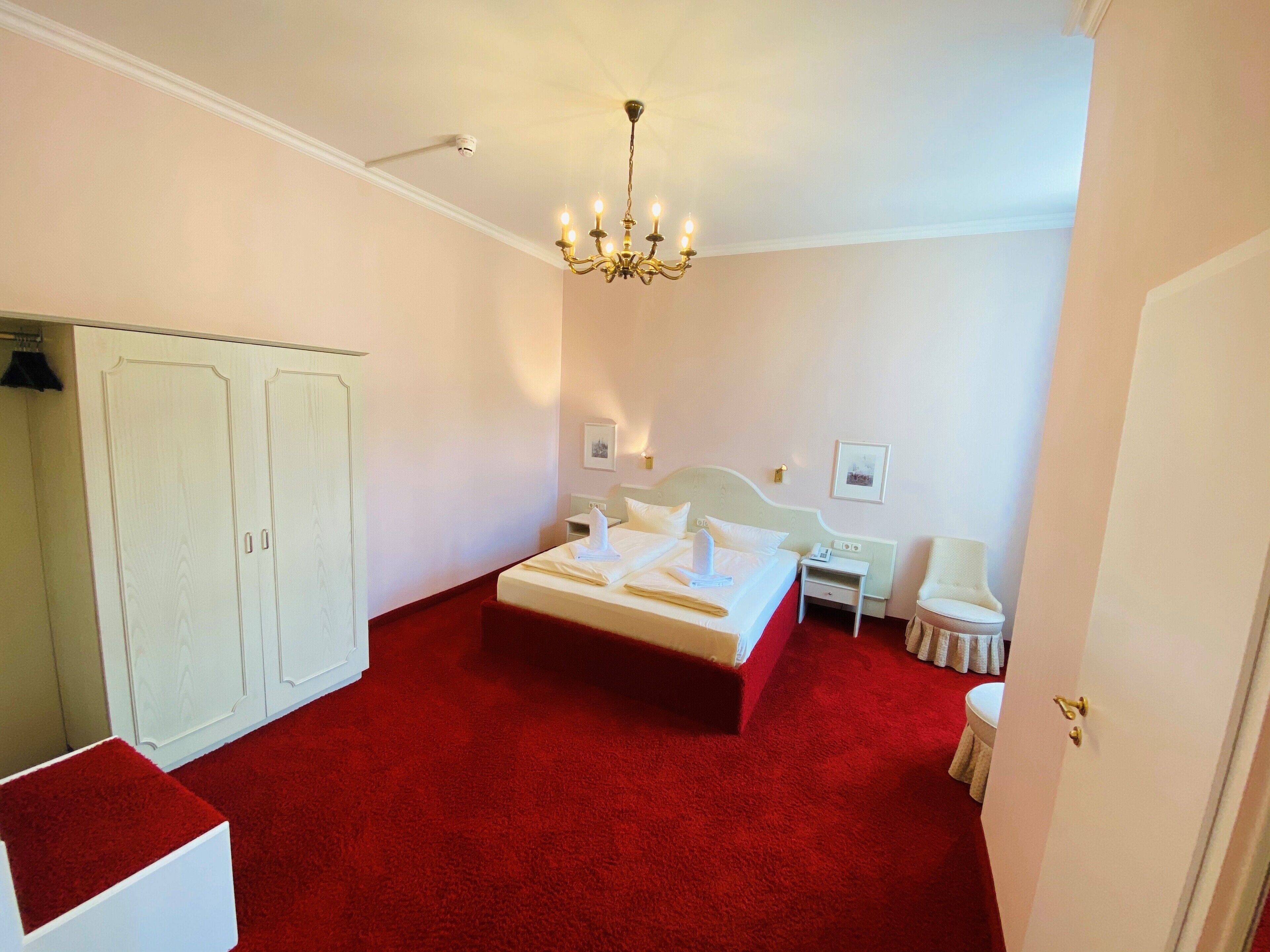 Una habitación de hotel con una cama grande, un armario, un escritorio y una silla.