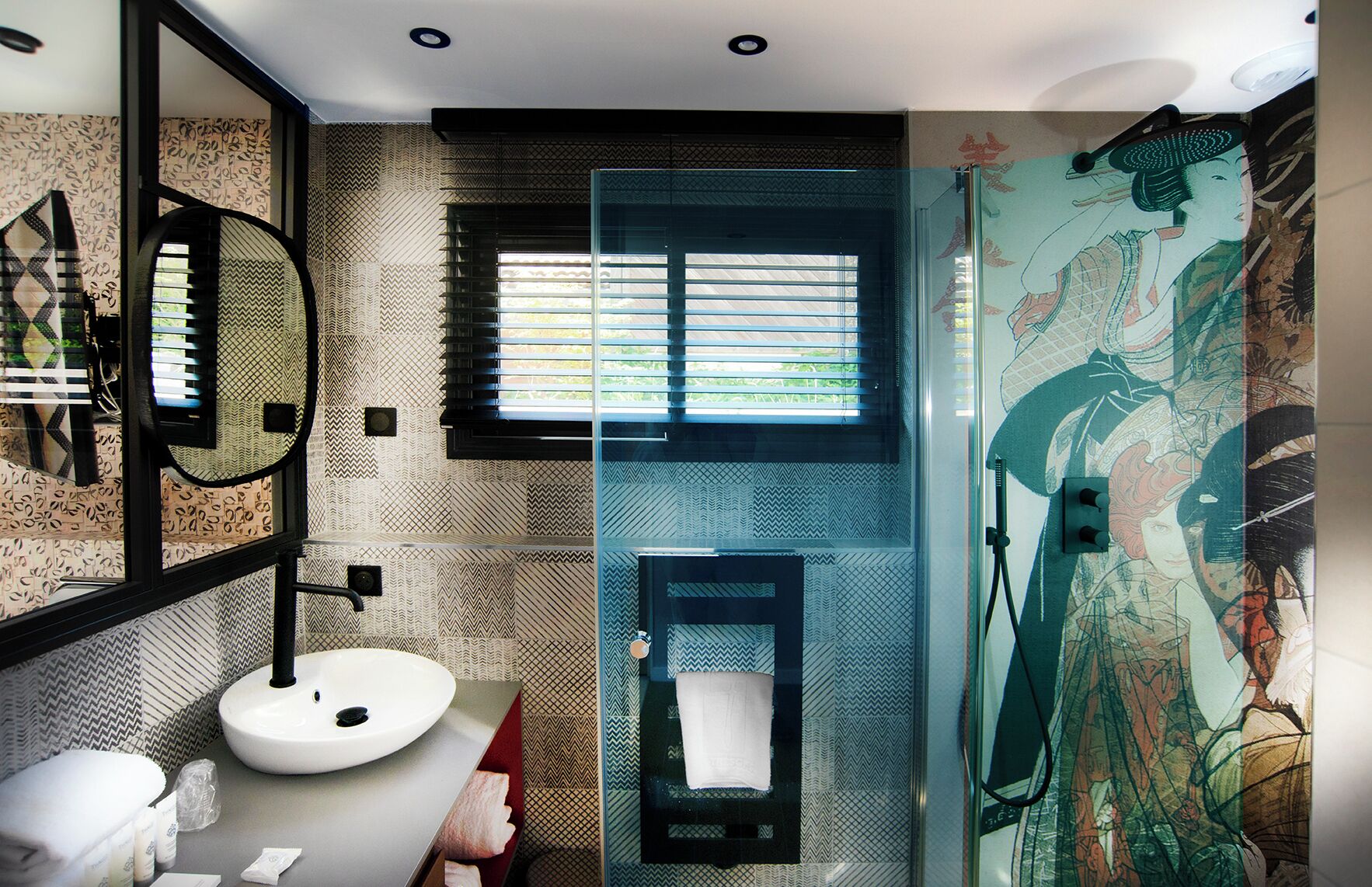 A bathroom with a modern design, featuring a large mirror, a sink, and a shower with a unique mural.