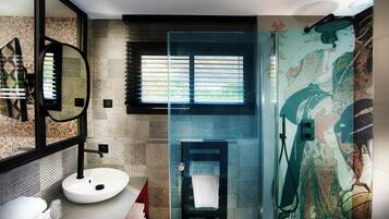 A bathroom with a modern design, featuring a large mirror, a sink, and a shower with a unique mural.