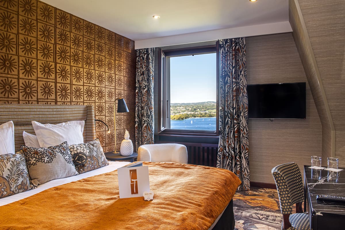 Habitación de hotel con una cama grande, televisión de pantalla plana, zona de comedor y vista al paisaje.