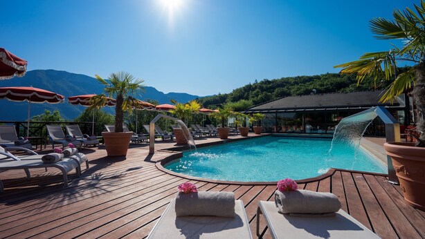 Un espace aménagé au bord de la piscine, avec des chaises longues, des parasols et une cascade décorative.
