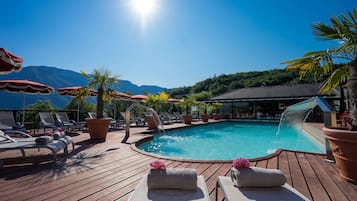 Una piscina al aire libre, sombrillas, sillones reclinables de piscina