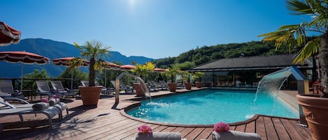 Una piscina al aire libre, sombrillas, sillones reclinables de piscina